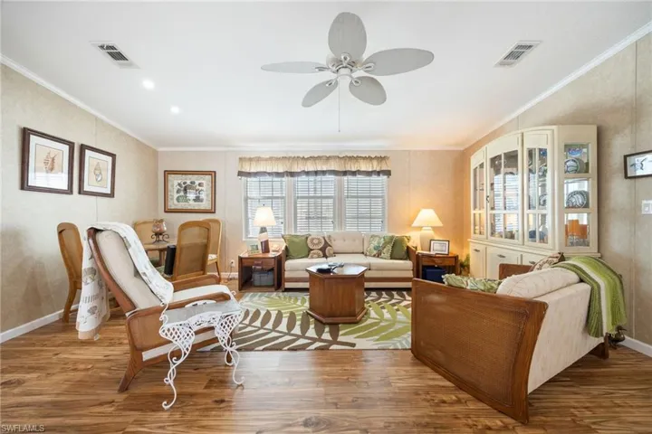 Living area with wood finished floors, crown molding, and a ceiling fan