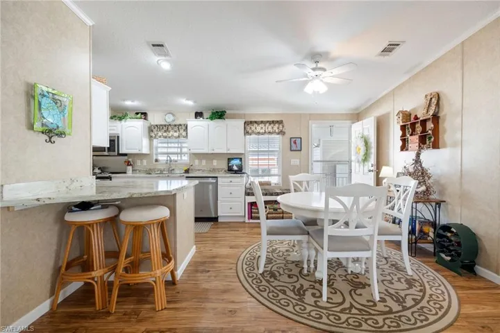 Dining space featuring light wood-style floors, a ceiling fan, crown molding, and a textured wall