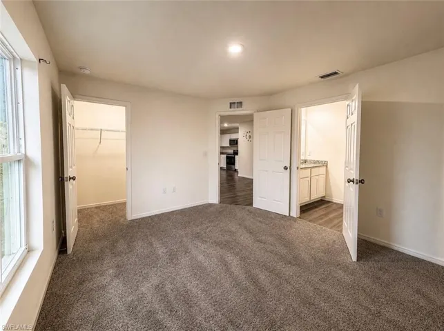 Carpeted room with white walls, recessed lighting, and a white window frame