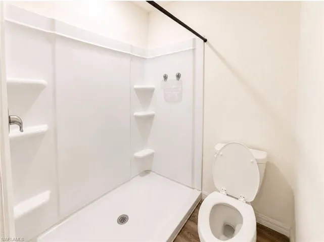 Integrated shower unit with built-in shelving, brushed nickel fixtures, and a coordinating toilet