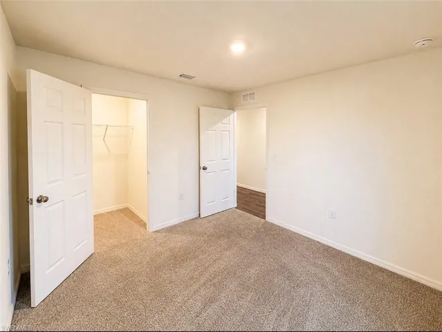 Carpeted room with neutral-toned walls, a recessed ceiling light, and white trim