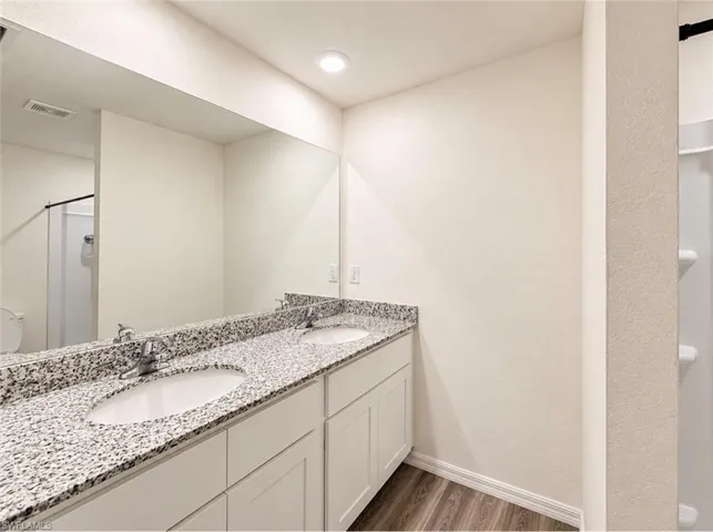 Dual vanity featuring light-toned cabinetry and speckled countertops