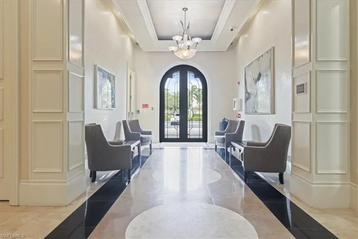 Foyer featuring inlaid floor details, a chandelier, crown molding, french doors, and arched walkways