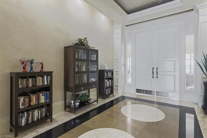 Entrance foyer with inlaid floor details, ornate columns, and ornamental molding