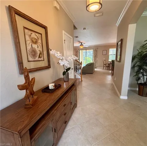 Hall featuring ornamental molding and light tile patterned flooring