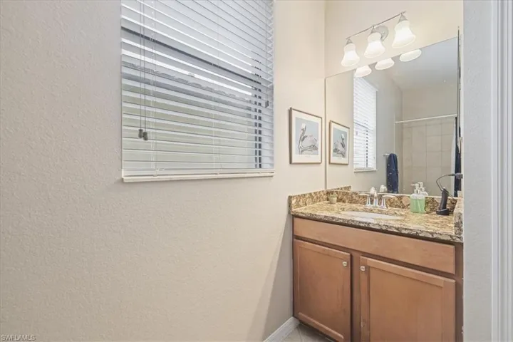 Bathroom featuring vanity, a textured wall, and a shower