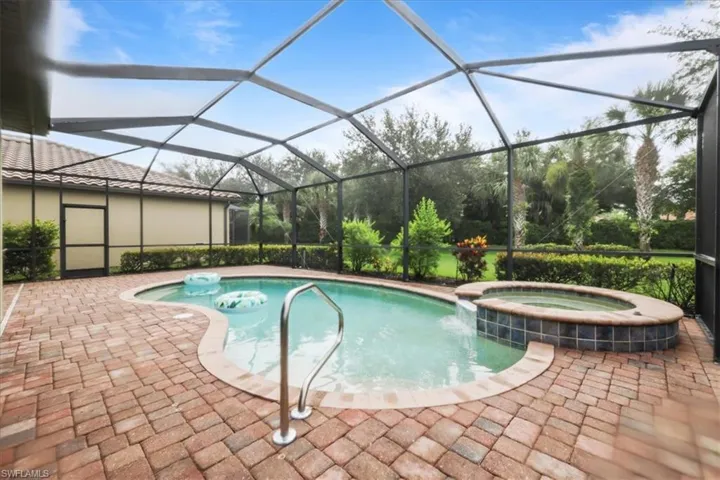 View of swimming pool with a pool with connected hot tub, a patio, and glass enclosure
