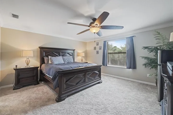 Bedroom with carpet flooring, ornamental molding, and a ceiling fan