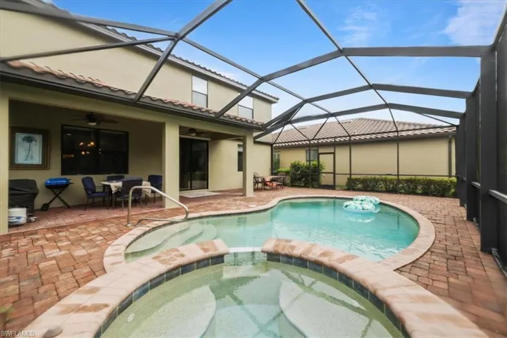 View of swimming pool with ceiling fan, a pool with connected hot tub, a patio area, and outdoor dining area
