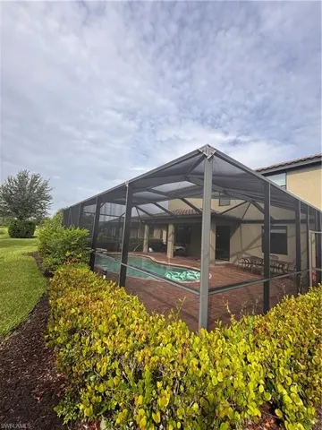 View of patio / terrace with a sunroom, an outdoor pool, a deck, and glass enclosure