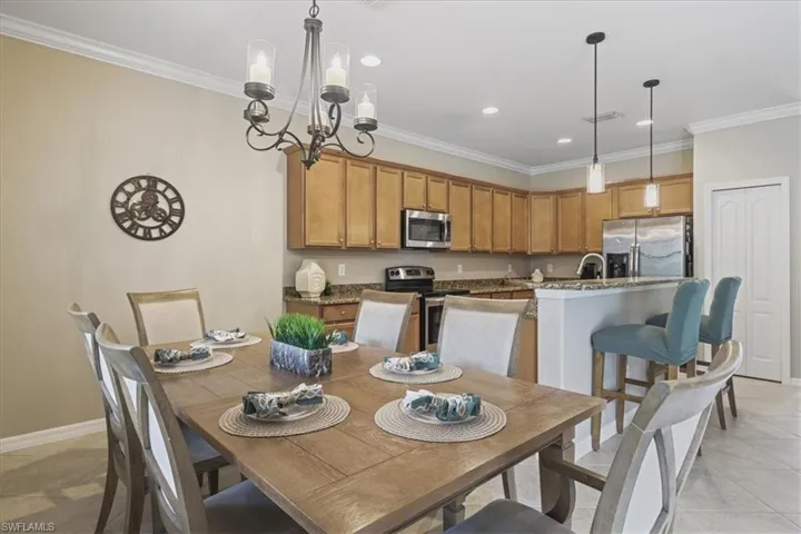Dining area with ornamental molding, a chandelier, recessed lighting, and light tile patterned floors