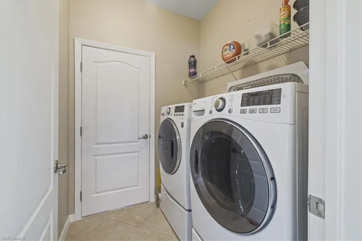 Laundry area with washer and clothes dryer and light tile patterned flooring