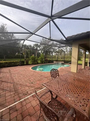 View of pool featuring a patio area, a sunroom, a lanai, and a pool with connected hot tub