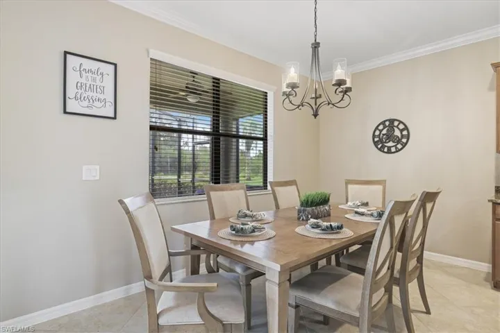 Dining space with crown molding, a chandelier, and light tile patterned floors