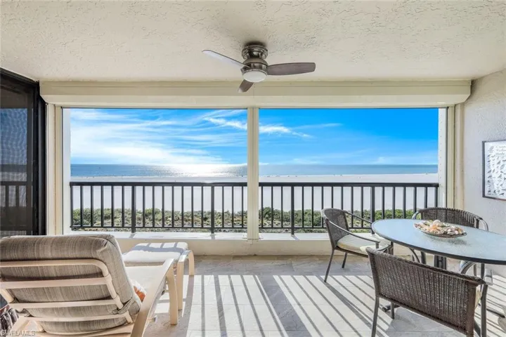 Sunroom / solarium featuring ceiling fan, plenty of natural light, a water view, and a view of the beach