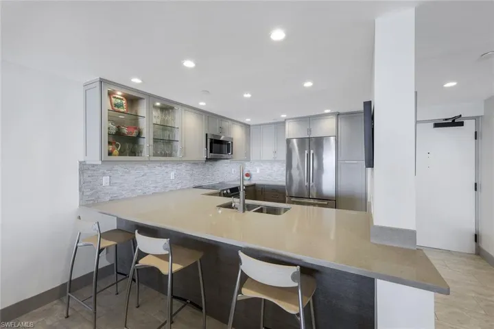 Kitchen with sink, kitchen peninsula, decorative backsplash, a breakfast bar, and appliances with stainless steel finishes