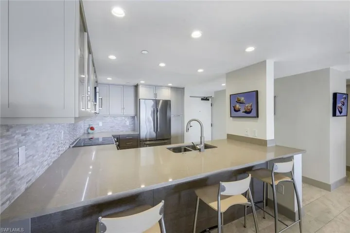 Kitchen with kitchen peninsula, high end refrigerator, tasteful backsplash, sink, and a breakfast bar area