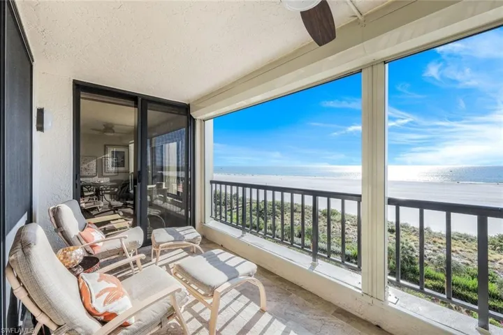 Balcony featuring a beach view, a water view, and ceiling fan