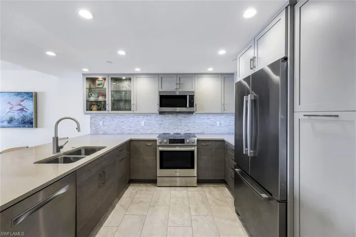 Kitchen featuring gray cabinetry, sink, stainless steel appliances, tasteful backsplash, and kitchen peninsula