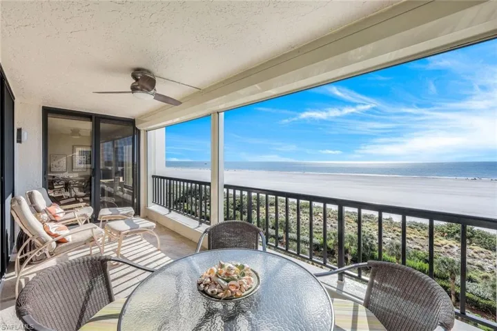 Balcony featuring a beach view, a water view, and ceiling fan