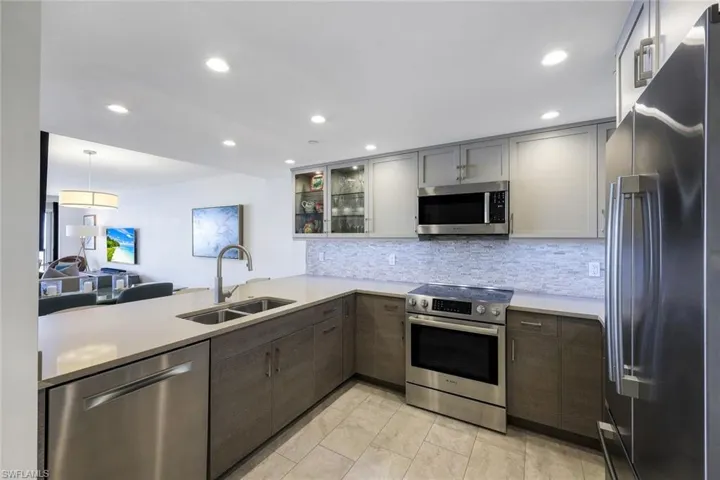Kitchen with kitchen peninsula, appliances with stainless steel finishes, tasteful backsplash, sink, and pendant lighting