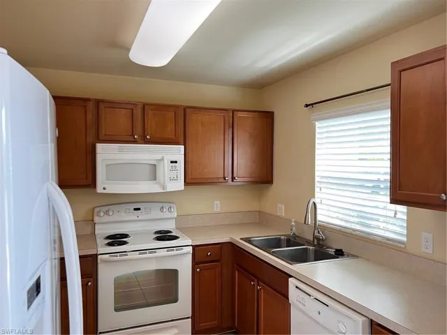 Kitchen featuring range, a sink, fridge, dishwasher, and brown cabinetry