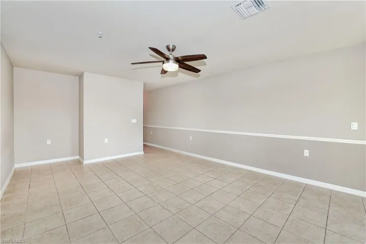 Unfurnished room featuring a ceiling fan, light tile patterned floors, a pendent fire sprinkler, and baseboards