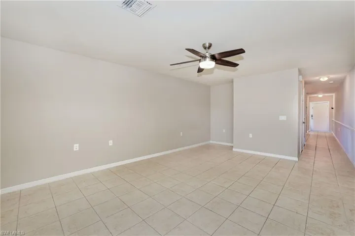 Spare room featuring ceiling fan, light tile patterned floors, and baseboards