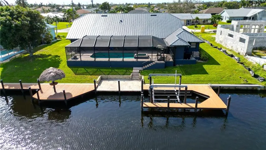 Dock area with a water view, a lawn, and a lanai