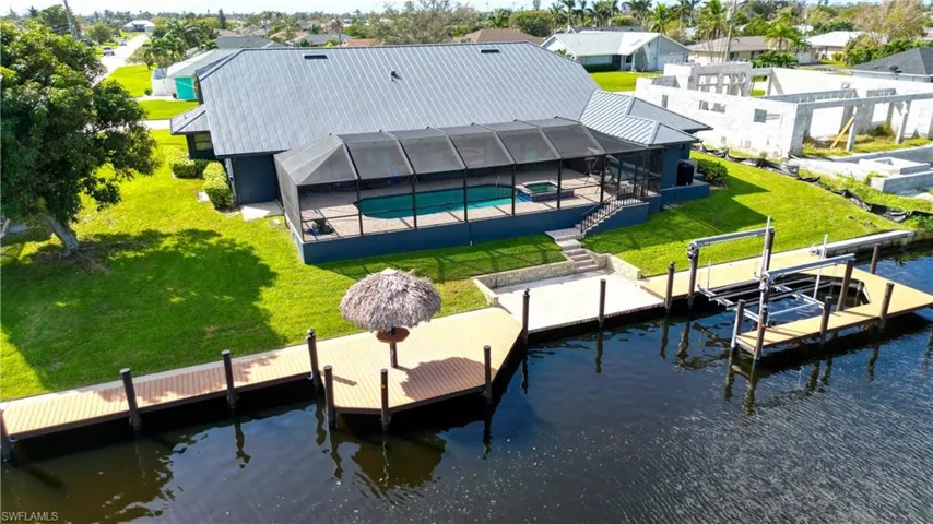 View of dock featuring a patio area, a lanai, a lawn, and a water view