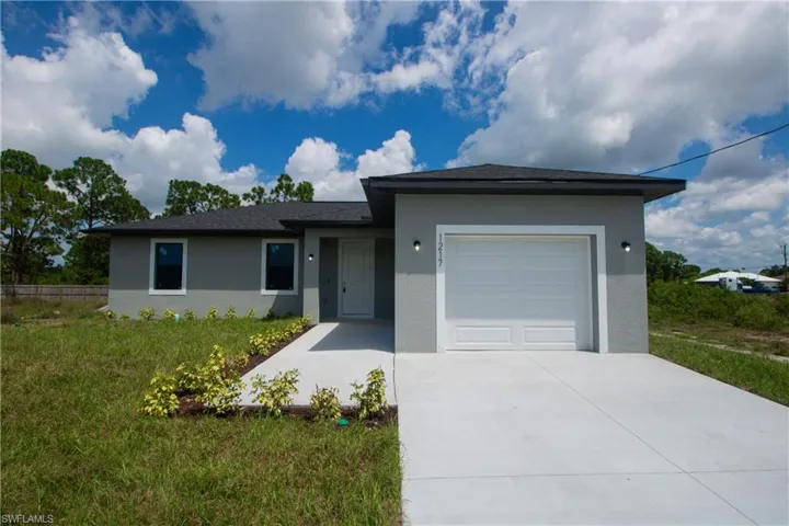 Single story home with stucco siding, an attached garage, and driveway.