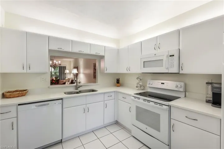 Kitchen with white cabinets, light tile floors, white appliances