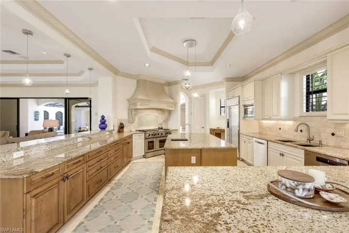 Spacious kitchen with a gorgeous hood and glass backsplash, large stainless refrigerator, designer led lighting, granite countertops, prep island with sink, loads of storage all in a great room floor plan.