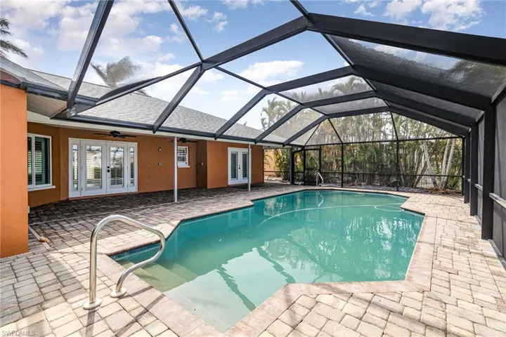 View of swimming pool with french doors, a patio, glass enclosure, and ceiling fan