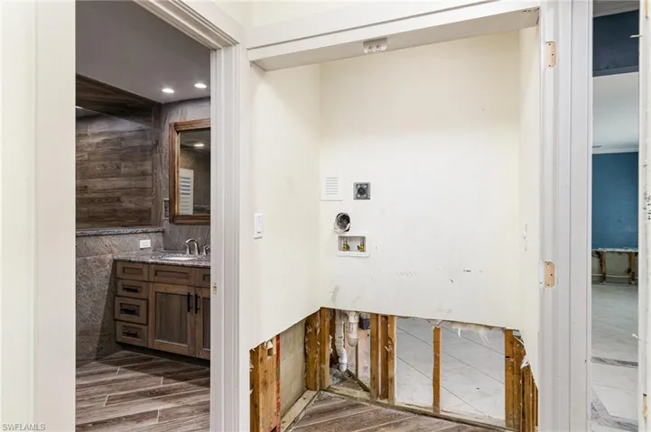 Laundry in Primary Bedroom  with tile flooring, hookup for a washing machine, hookup for an electric dryer, sink, and tile walls