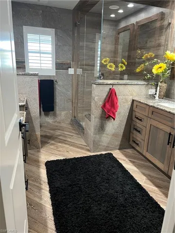 Prior to Hurricane  Helene Primary Bathroom featuring tile walls, vanity, tile  floors, and walk in shower
