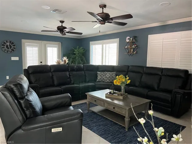 Prior to Hurricane  Helene Tiled living room featuring ceiling fan, ornamental molding, and plenty of natural light