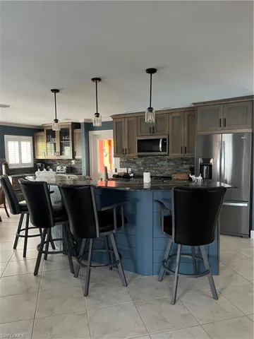 Prior to Hurricane  Helene  Kitchen featuring refrigerator, a kitchen breakfast bar, pendant lighting, and backsplash