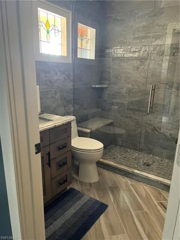 Prior to Hurricane  Helene Guest  Bathroom with tile walls, vanity, toilet, and an enclosed shower
