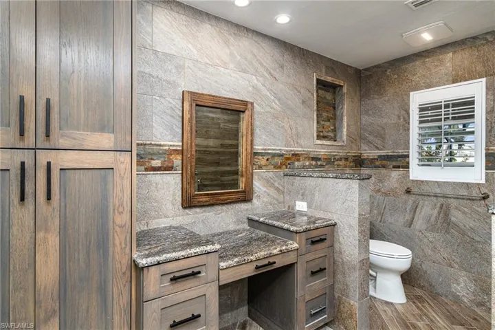 Primary Bathroom featuring vanity, toilet, hardwood / wood-style flooring, and tile walls