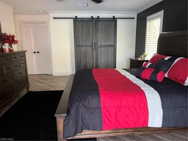 Prior to Hurricane  Helene  Primary Bedroom featuring ornamental molding, a barn door, tile flooring, and a closet
