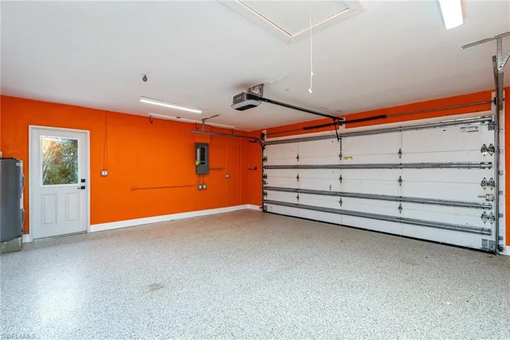 Garage with a garage door opener, electric panel, and water heater