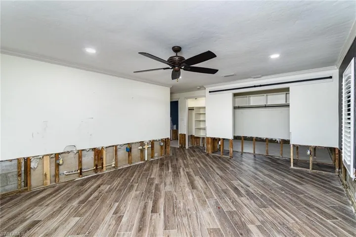 Primary bedroom with a closet, crown molding, hardwood / tile  flooring, and ceiling fan