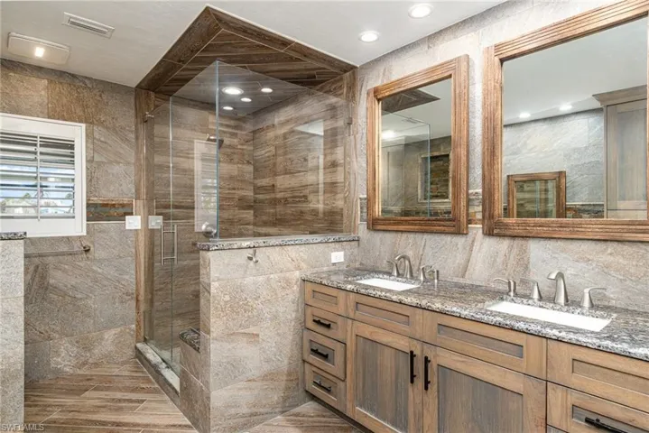 Primary Bathroom featuring vanity, tile walls, and walk in shower
