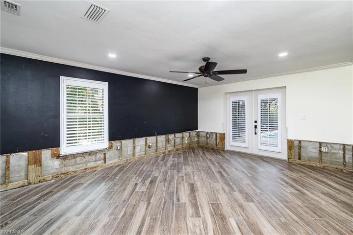 Primary living room with ornamental molding, ceiling fan, light tile flooring, and plenty of natural light