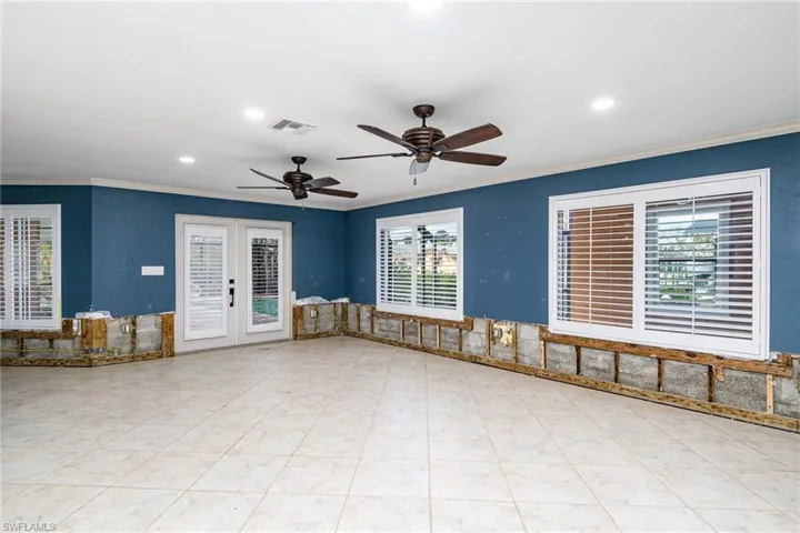 Family room with french doors, ceiling fan, a healthy amount of sunlight, and crown molding
