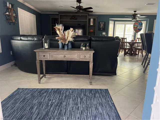 Prior to Hurricane  Helene Tiled living room featuring ornamental molding and ceiling fan
