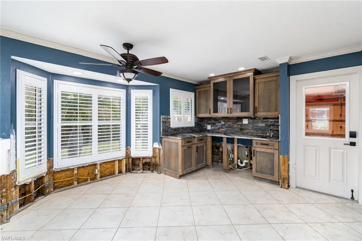 Dinette & wet bar area featuring ornamental molding, ceiling fan, light tile patterned floors, and backsplash