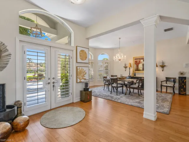 Foyer with light wood-type flooring, visible vents, a notable chandelier, french doors, and ornate columns