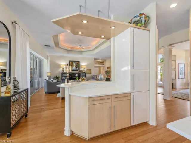 Kitchen with a raised ceiling, light wood-type flooring, open floor plan, and light brown cabinetry
